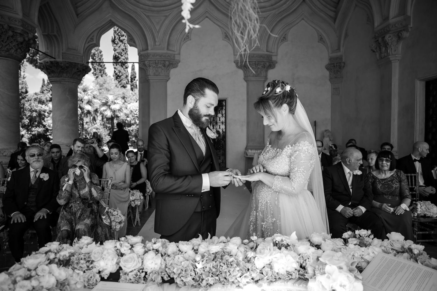 Black and white panoramic view of wedding ceremony in classical architectural setting.