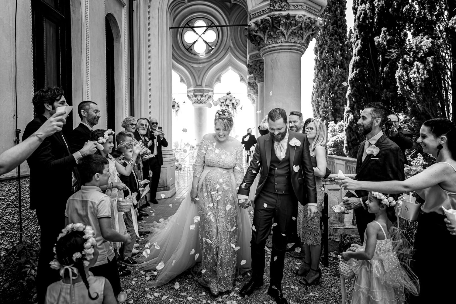 Wide angle shot of wedding ceremony with guests gathered in ornate columned space.