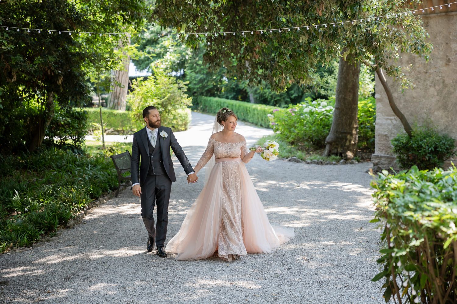 Romantic wedding photoshoot in a lush garden setting with classical architecture.