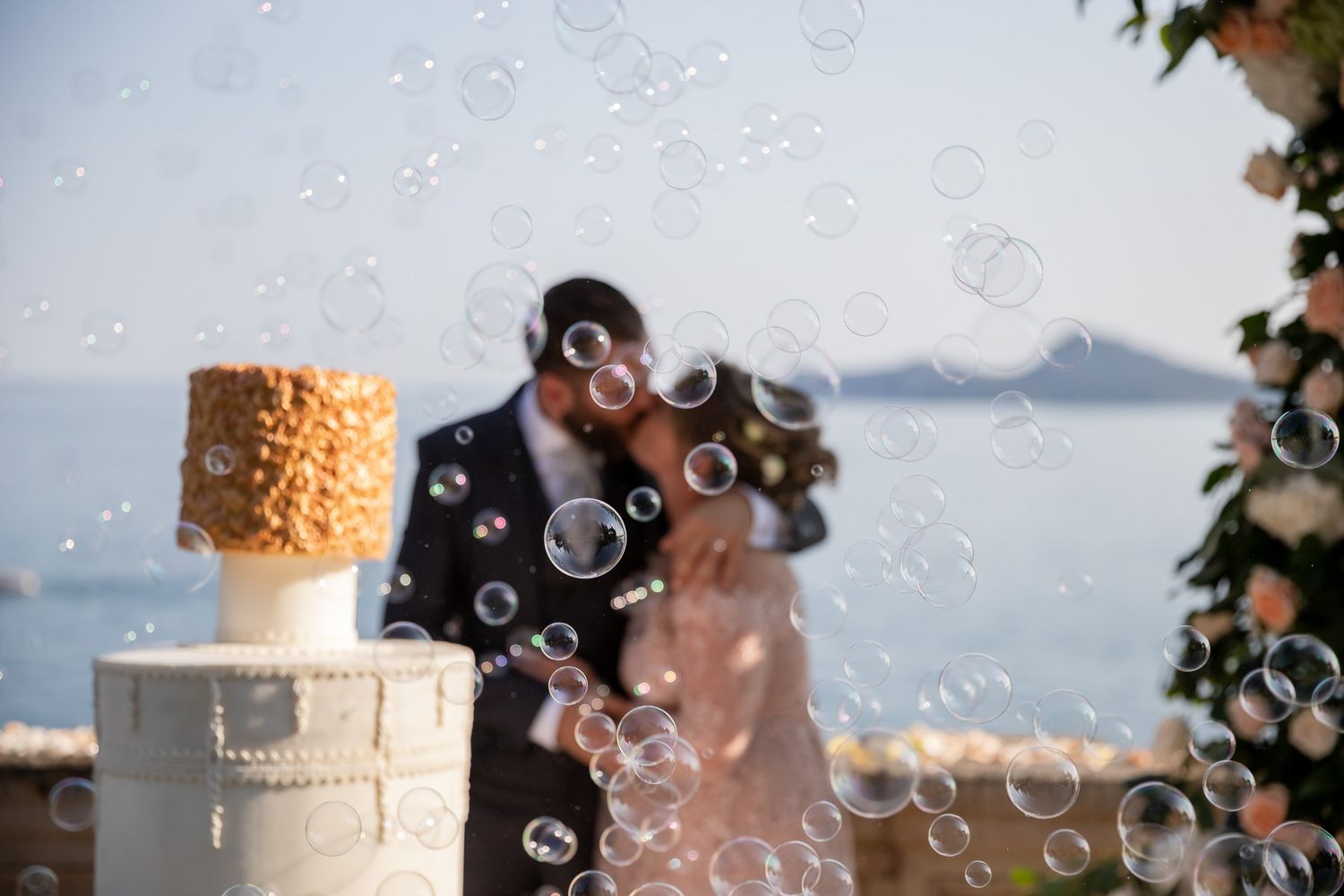 Wedding cake with bubbles floating in front creating a magical atmosphere by the ocean.