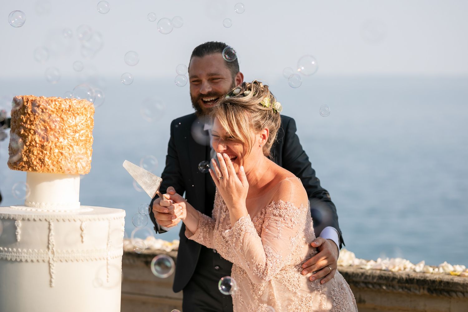 Joyful wedding moment with bubbles floating around a beautifully decorated cake.
