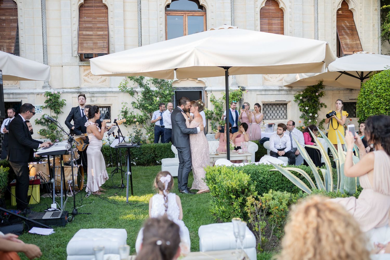 Outdoor wedding reception with white canopy tents and elegant garden setting.