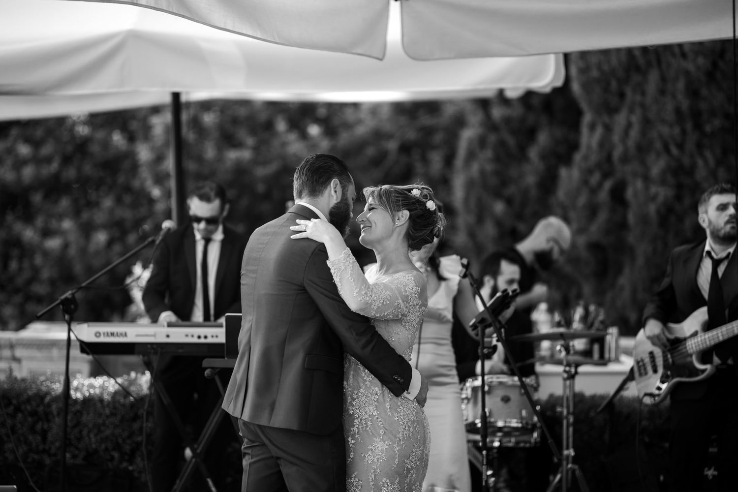 Elegant outdoor wedding reception under white canopies with guests seated at tables.