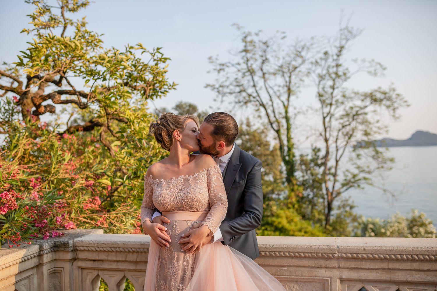 Romantic wedding portraits captured against a scenic coastal backdrop with stone architecture.