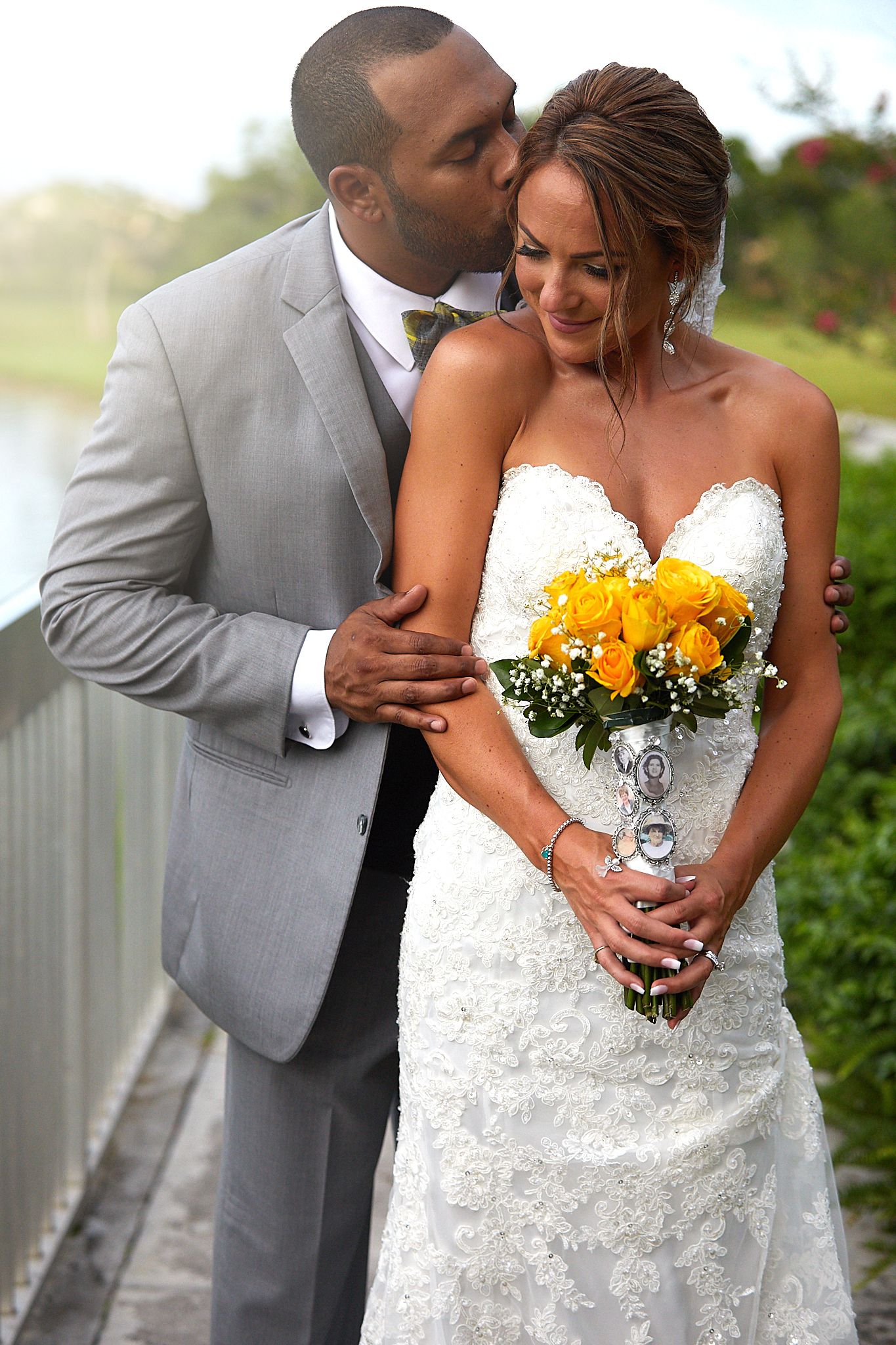 A romantic wedding portrait of a couple with yellow flowers on an outdoor boardwalk.