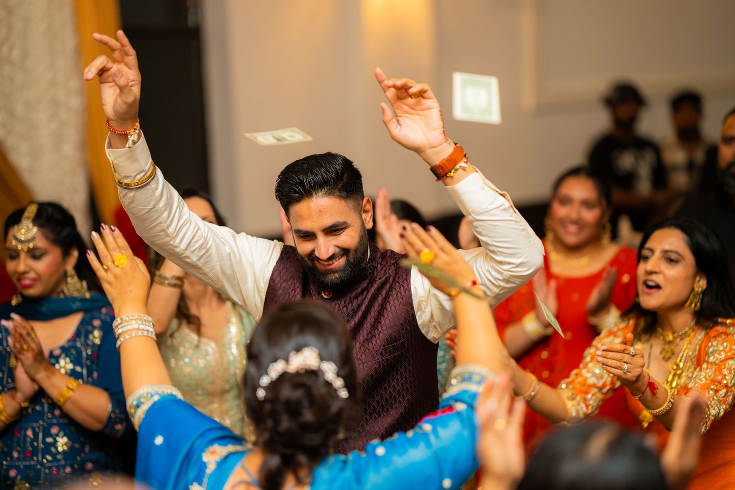 Energetic dance celebration at Indian wedding reception with guests in colorful attire.