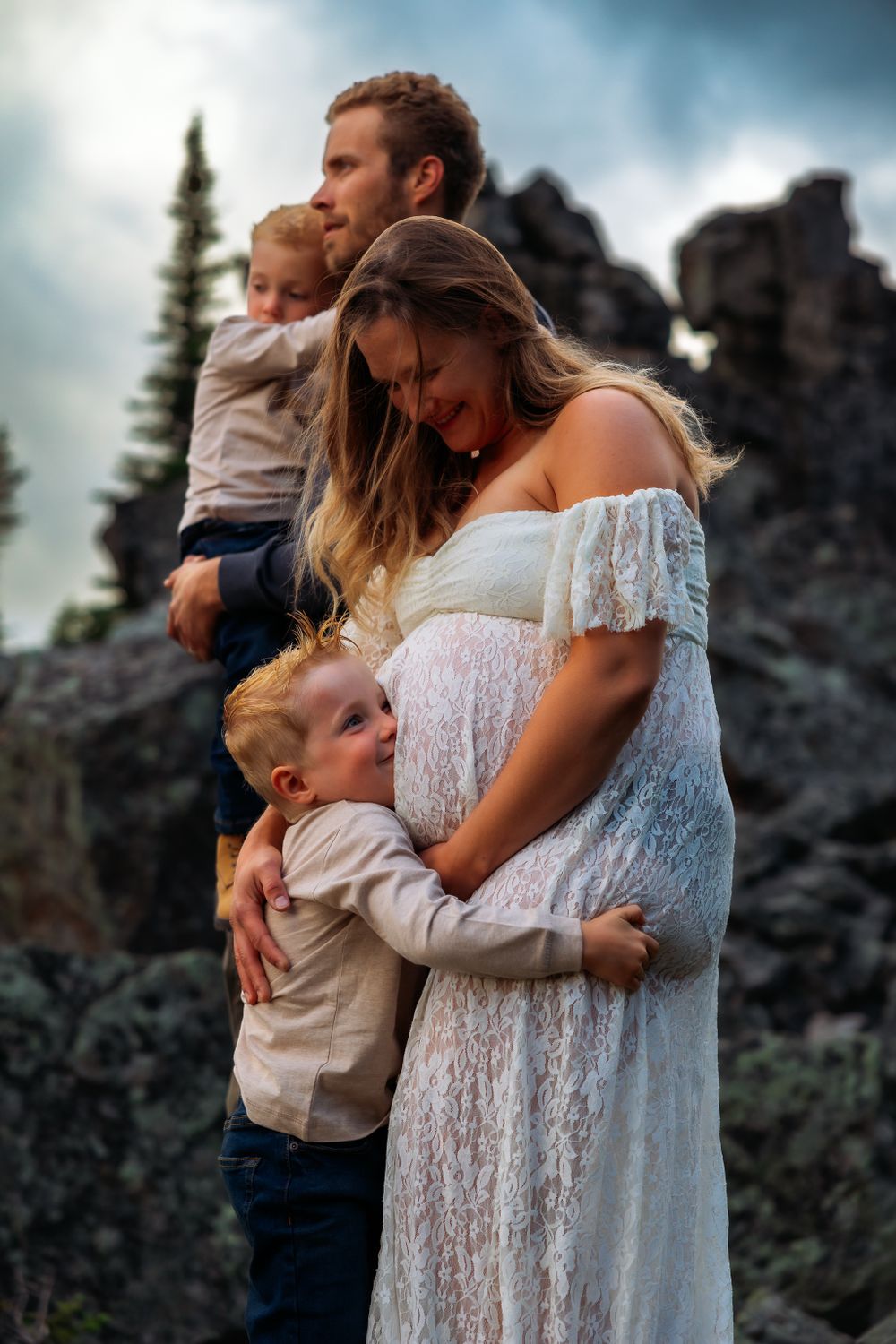 Family maternity photo in nature showing tender moments between parents, children and mother's pregnant belly.