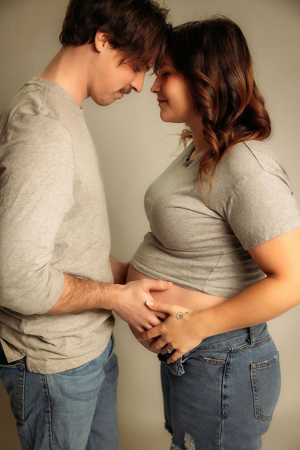 A series of intimate maternity photos showing a couple embracing and touching a pregnant belly.