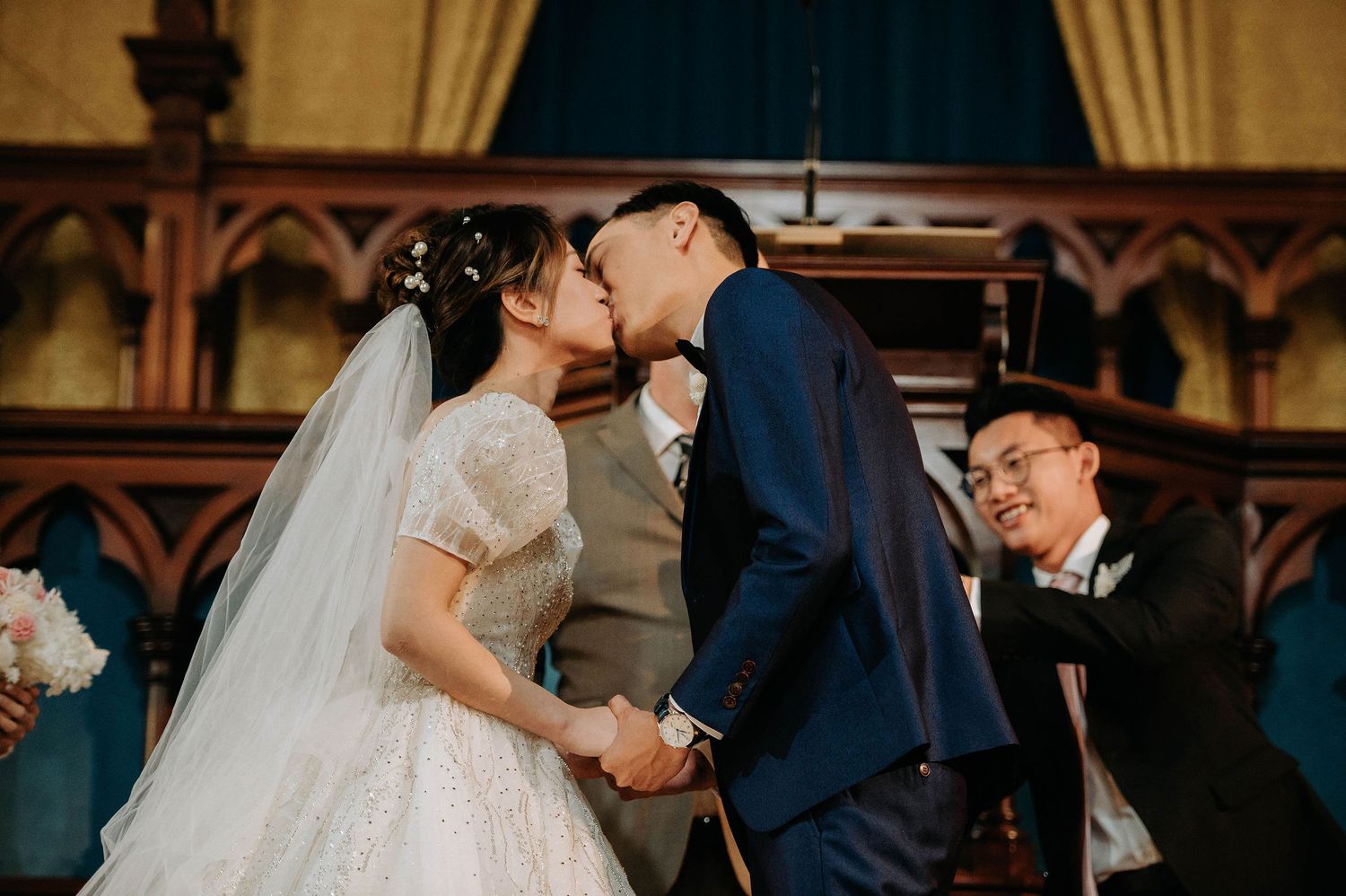 A romantic moment during a traditional church wedding ceremony with Gothic architectural details.