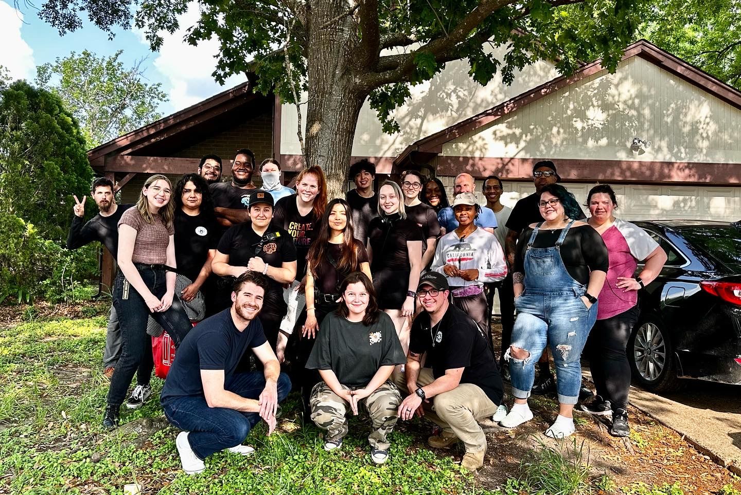 Large group of film crew members posing together outside a building.