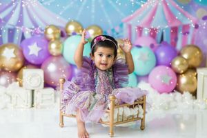 Carnival-themed birthday setup with circus tent backdrop and pastel balloon decorations.