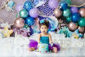 Blue and purple balloon arch backdrop with cake smash setup.