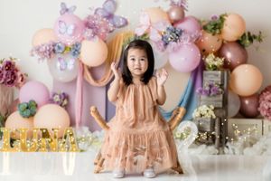 A peach dress against a backdrop of pastel balloons and decorative elements.