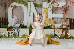 Safari-themed first birthday setup with giraffe, teddy bears, and floral decorations.
