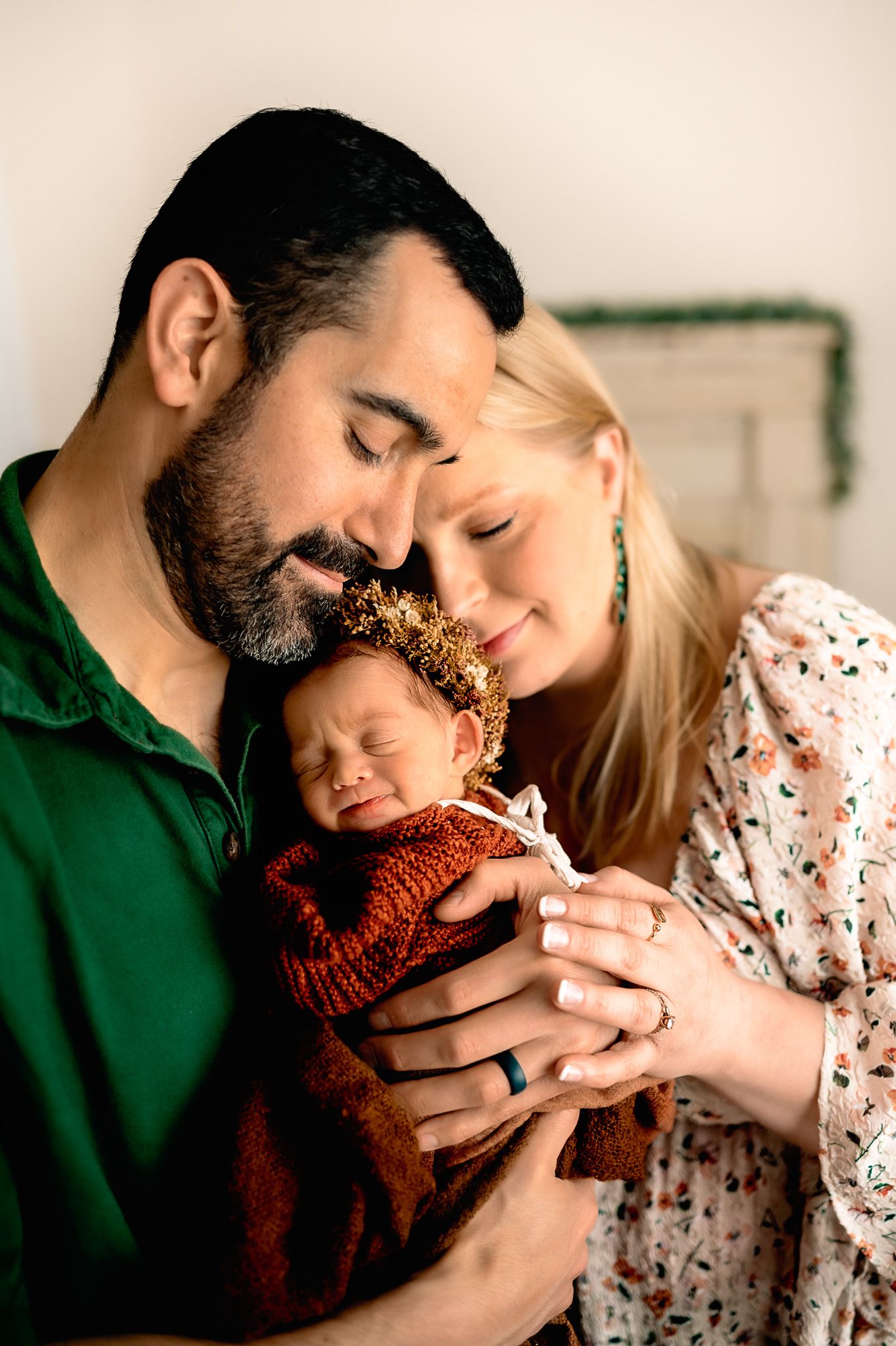 Intimate family moment with baby in red sweater being held by parents.