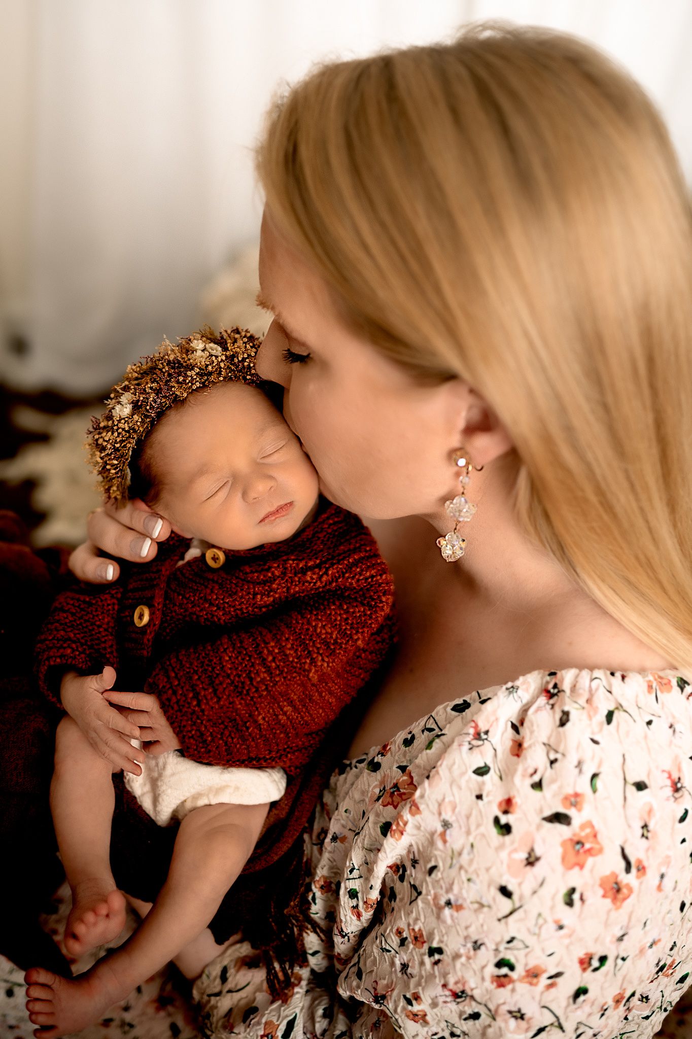 Tender moment between parent and infant wearing red knit sweater and gold crown.