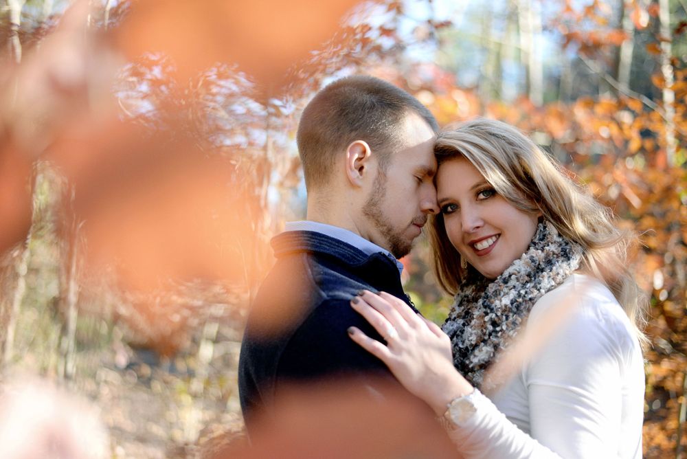 An intimate portrait through autumn leaves showing a tender embrace.