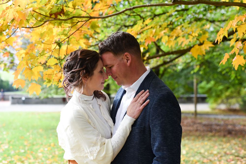 Romantic moment between couple under yellow fall foliage in the park.
