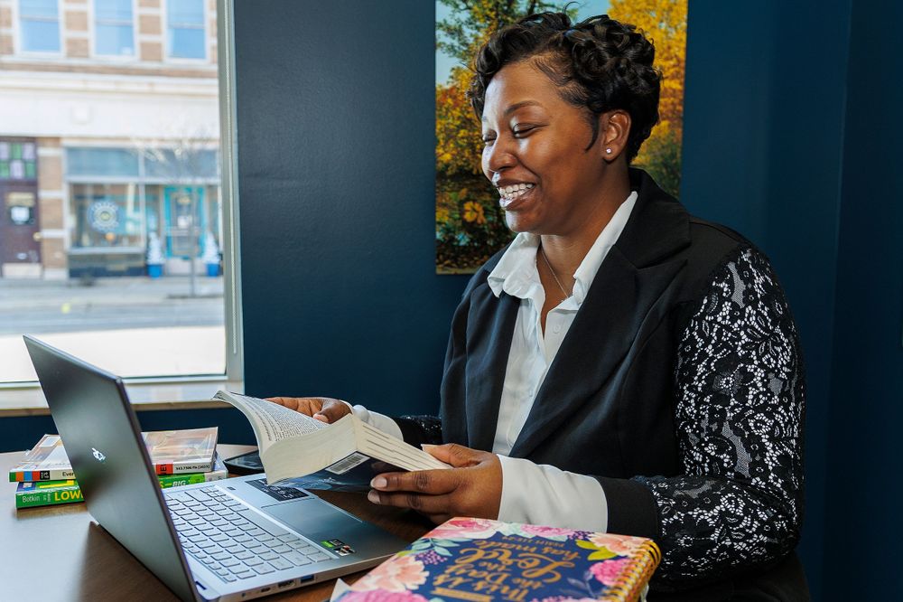 Business professional reviewing documents while working at laptop in office setting.