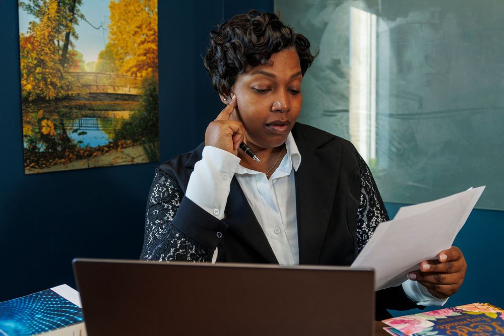 Professional reviewing paperwork while on phone call at office desk.