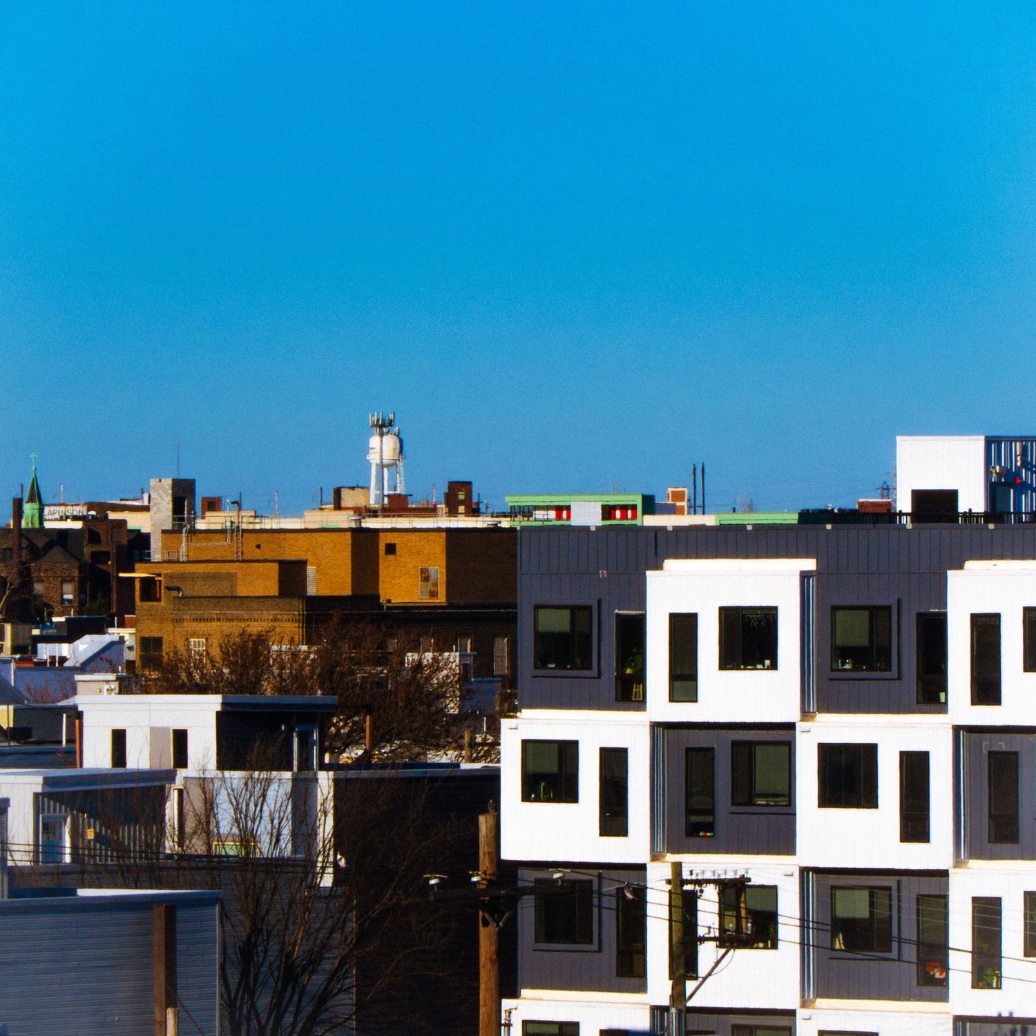 Modern urban cityscape with white apartment buildings against bright blue sky.