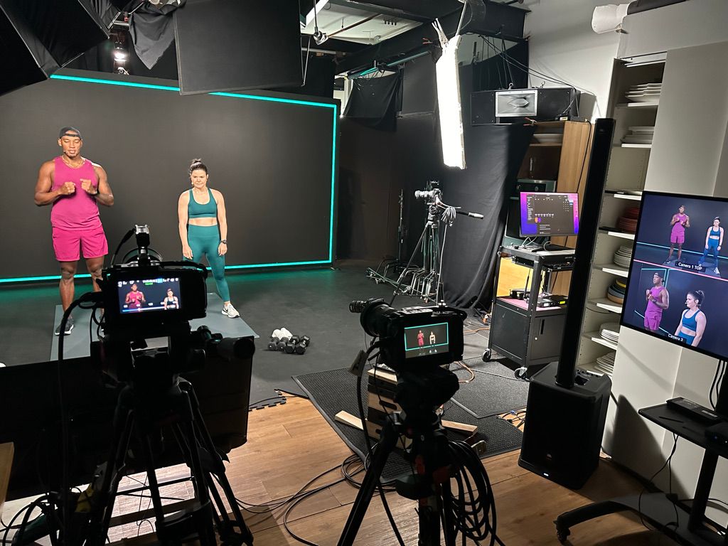 Two instructors from Swerve fitness premium cycling workouts live streaming fitness to gyms around the world in front of the 20'x8' LED wall