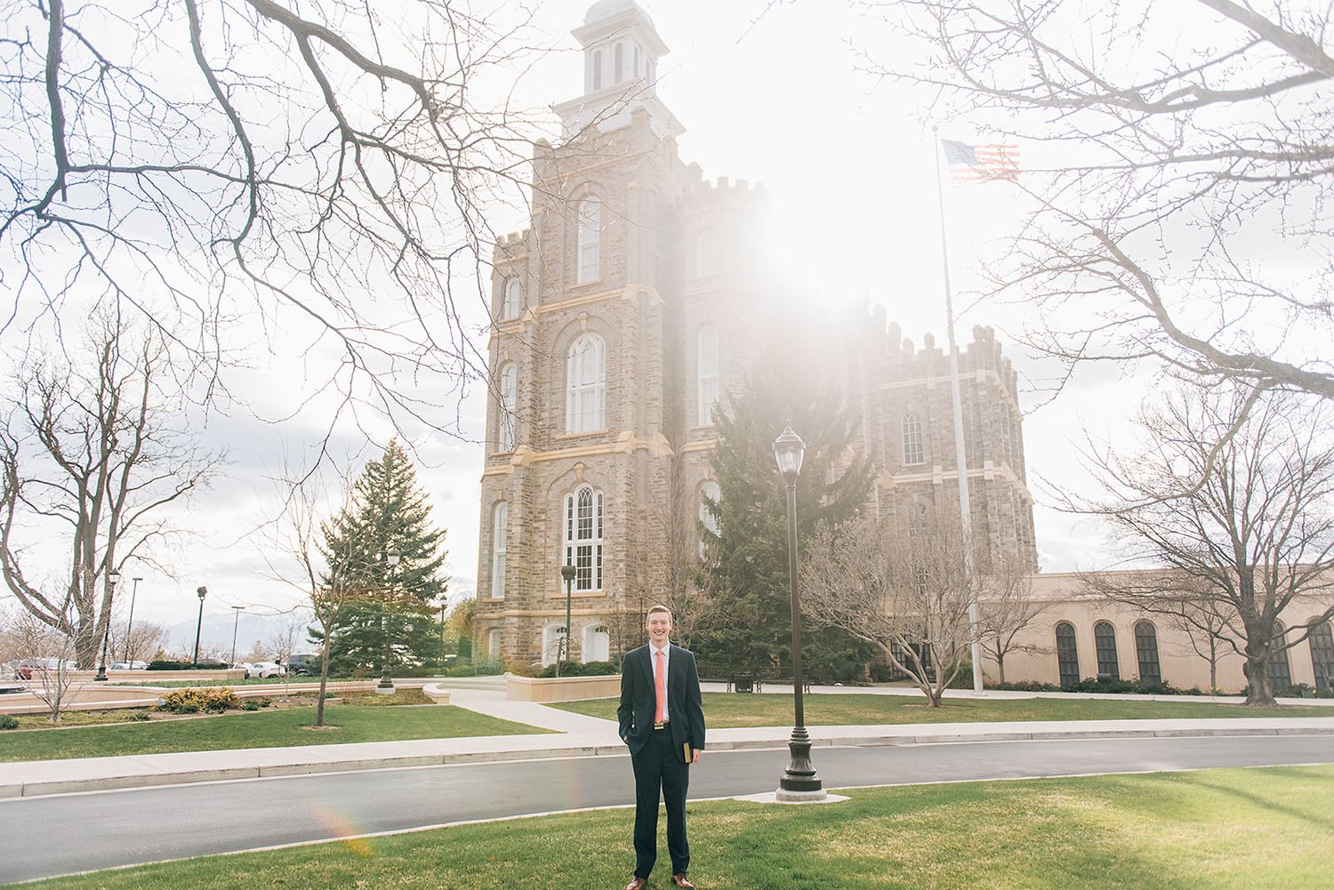 Person in dark suit standing in front of a towering historic church building on a cloudy day.