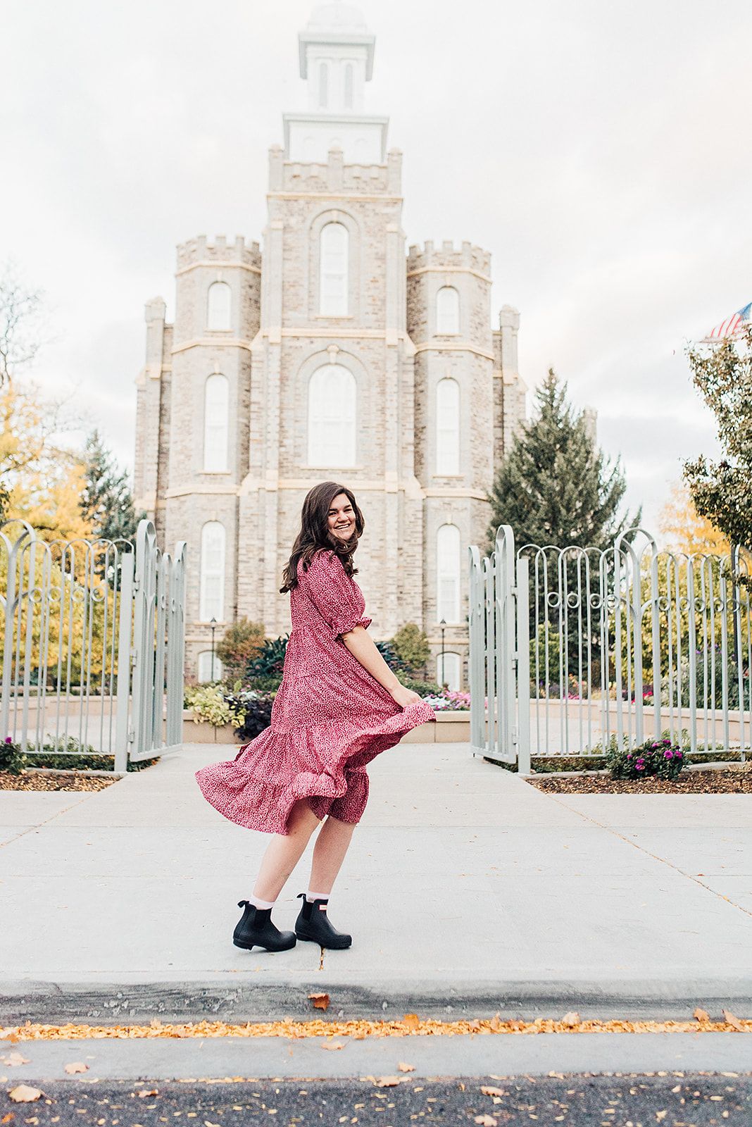 Someone twirling in a flowing pink dress in front of a historic temple building.