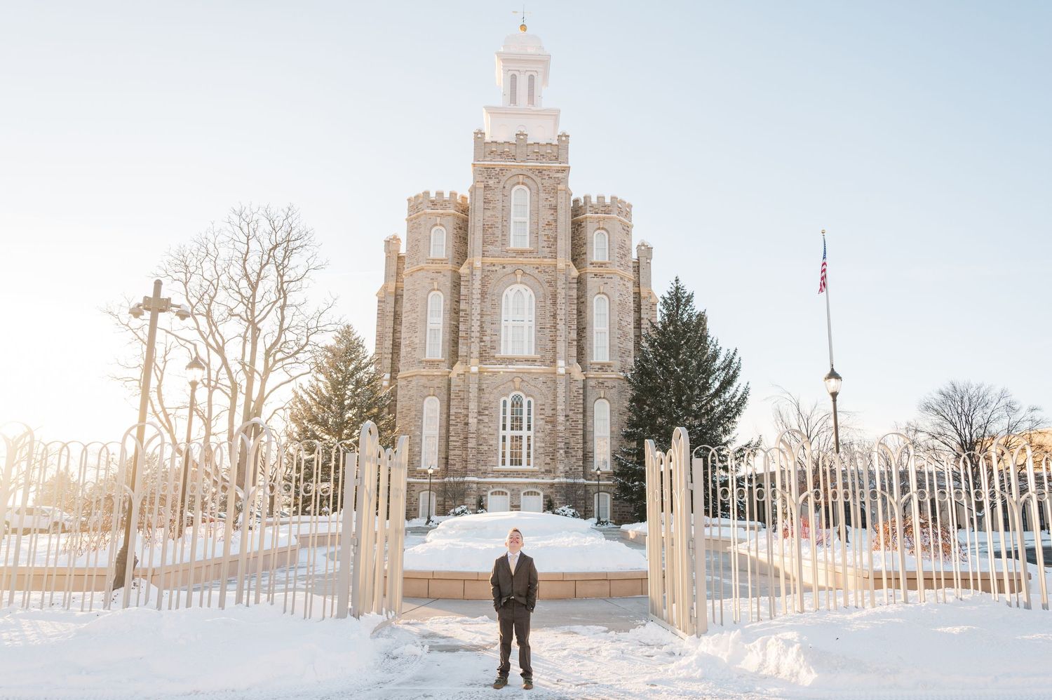 Person standing in front of grand Mormon temple during winter with snow on ground.