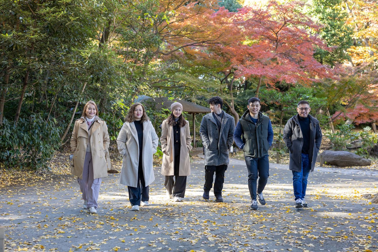 Group walking together on path surrounded by vibrant autumn maple trees.