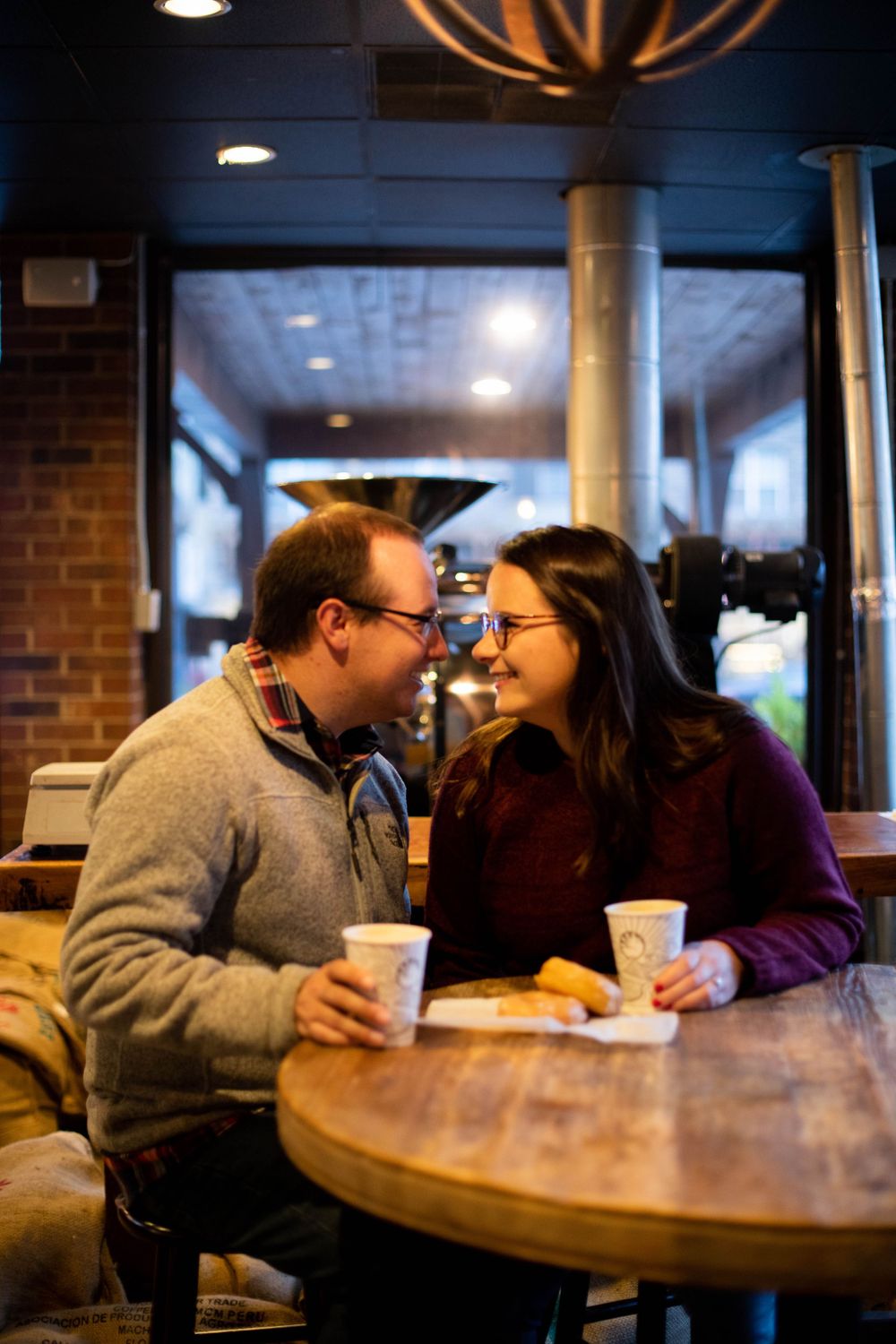 Couple sharing a romantic moment at a coffee shop with brick walls.