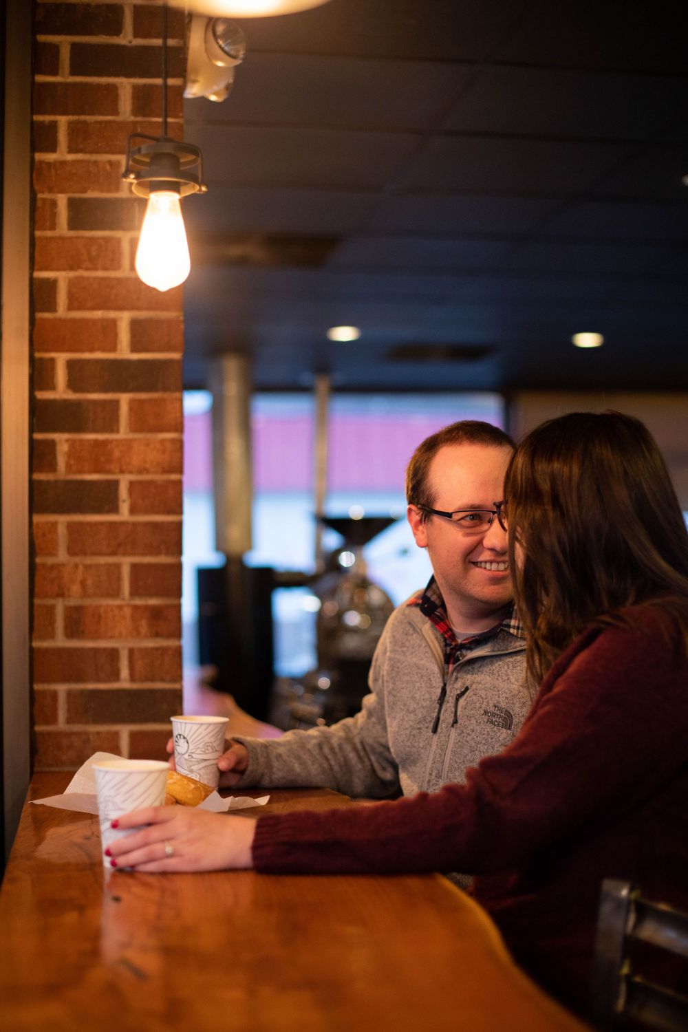 Couple having coffee together at a cozy cafe with brick walls.
