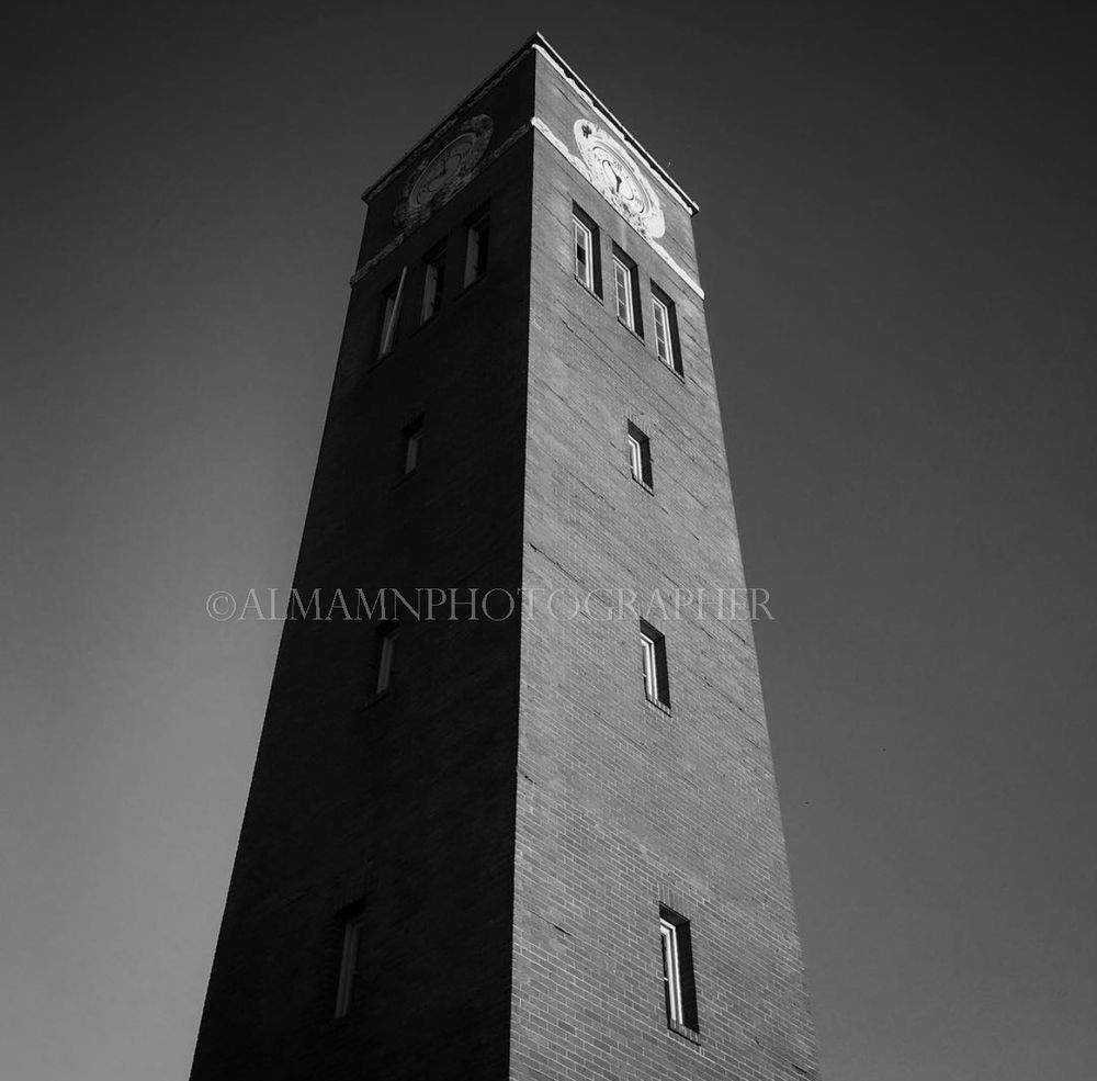 A tall brick tower photographed in black and white against a dark sky.
