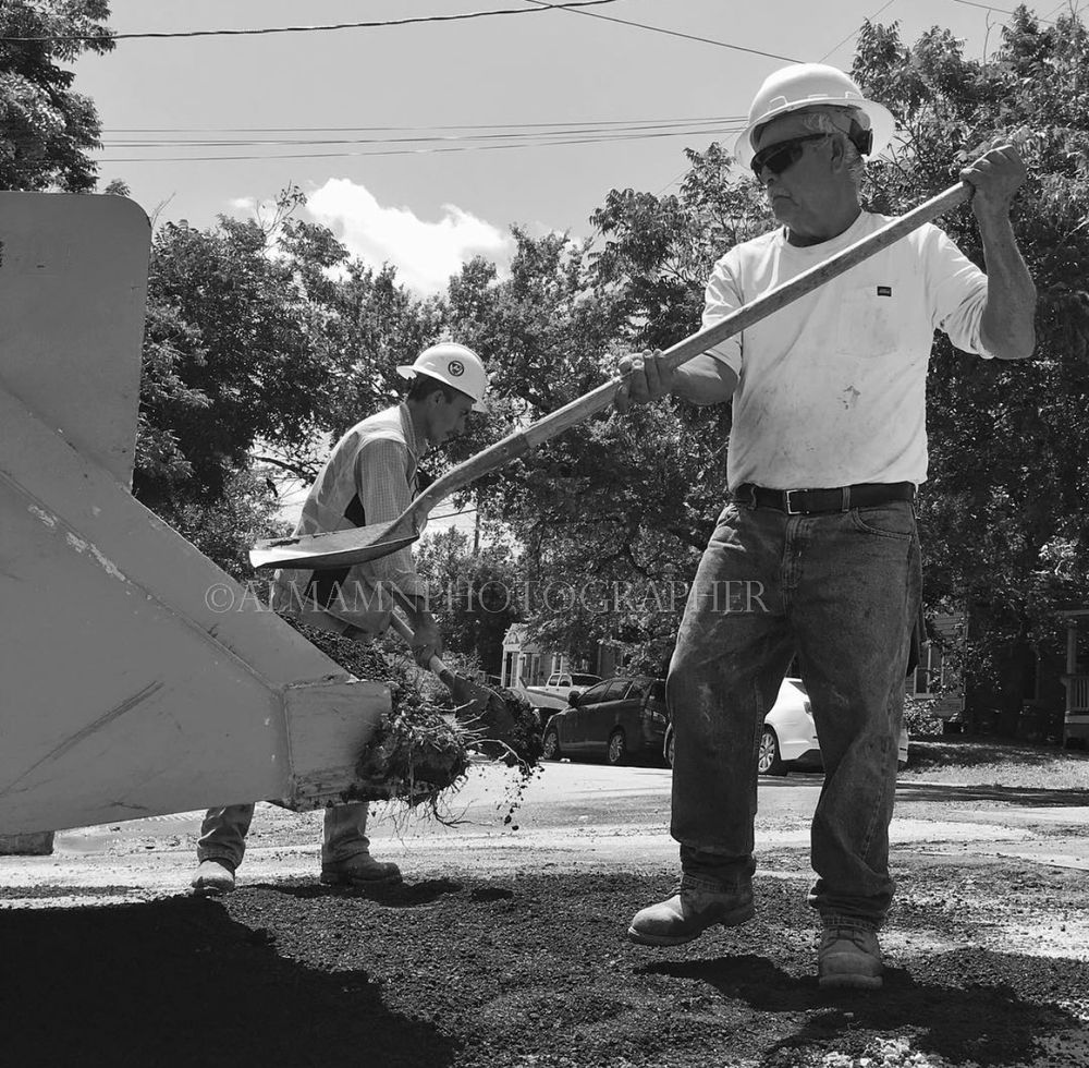 Workers in hard hats performing maintenance tasks in an outdoor setting.