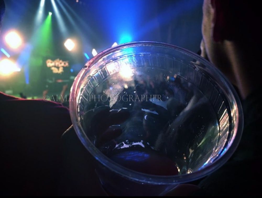 Martini glass illuminated by colorful nightclub lights in the background.