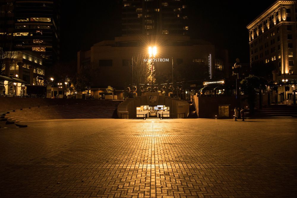 Illuminated street lamp casts warm light over empty brick plaza at night in urban setting.