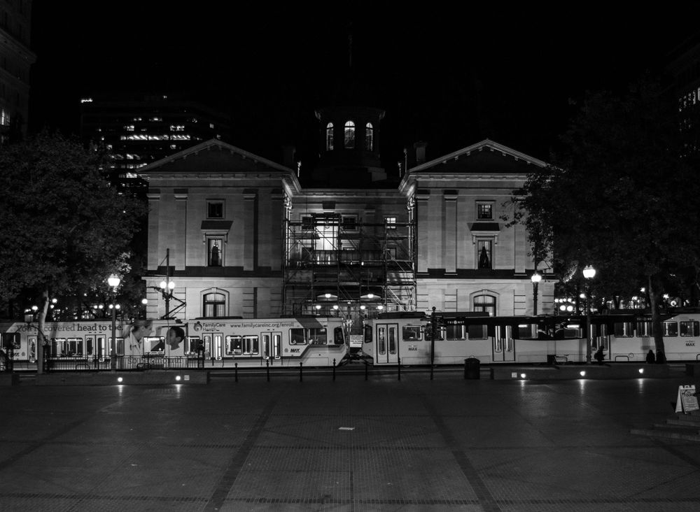Historic government building facade photographed in black and white at night with dramatic lighting.