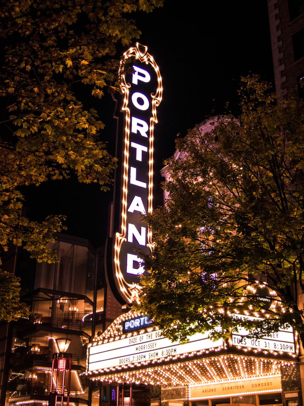 Historic Portland theater sign glowing with bright lights against dark sky.