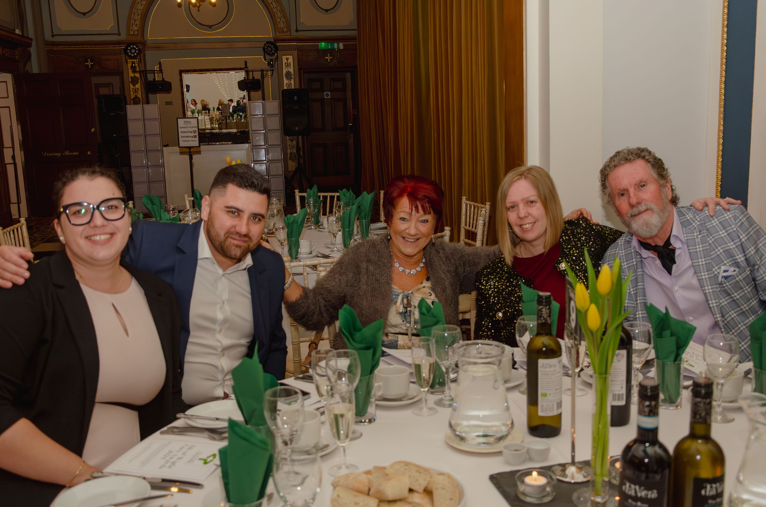 Group enjoying dinner and drinks at formal restaurant table.