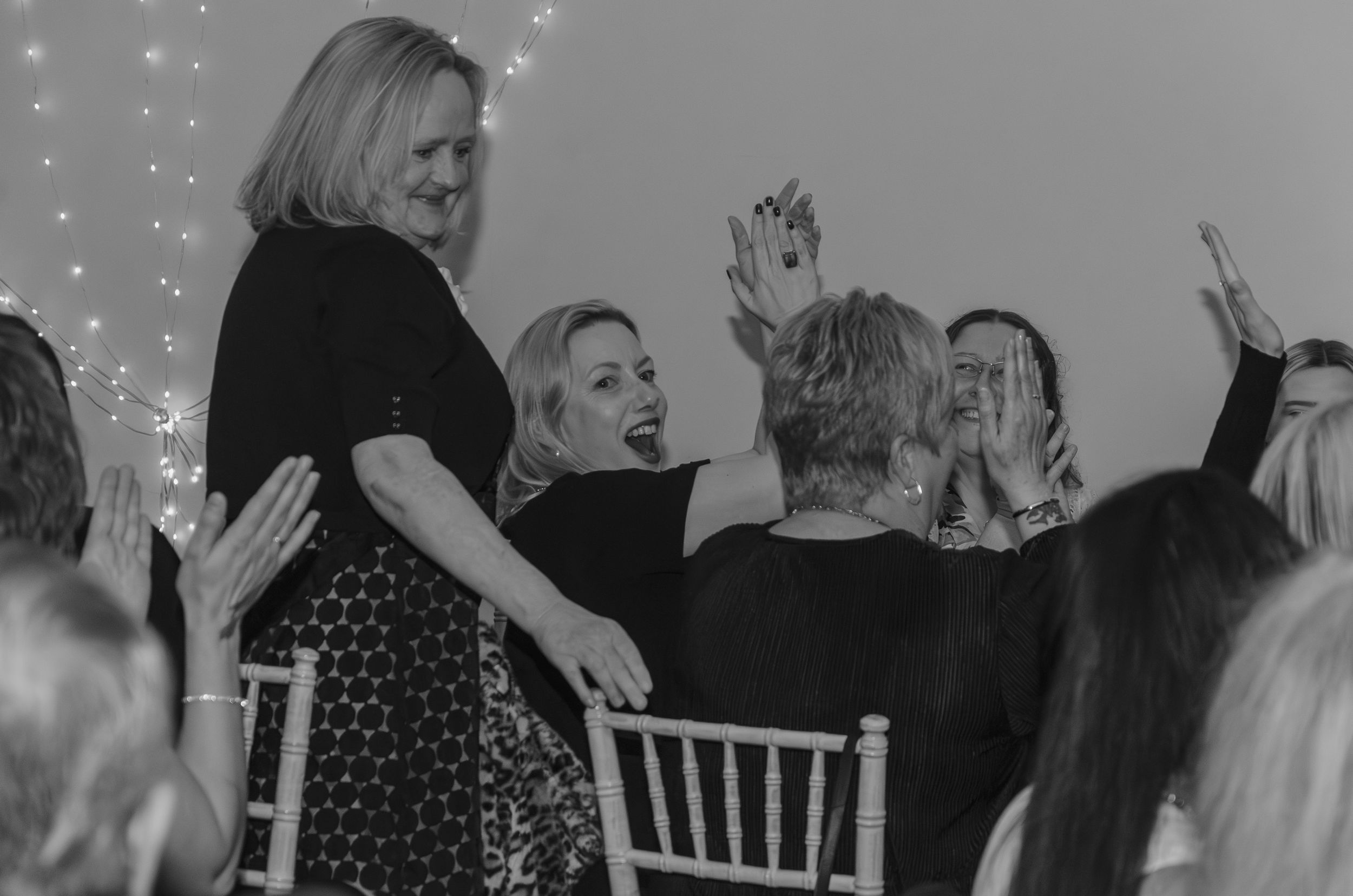 Event attendees raise their hands in celebration during a festive moment at a formal gathering.