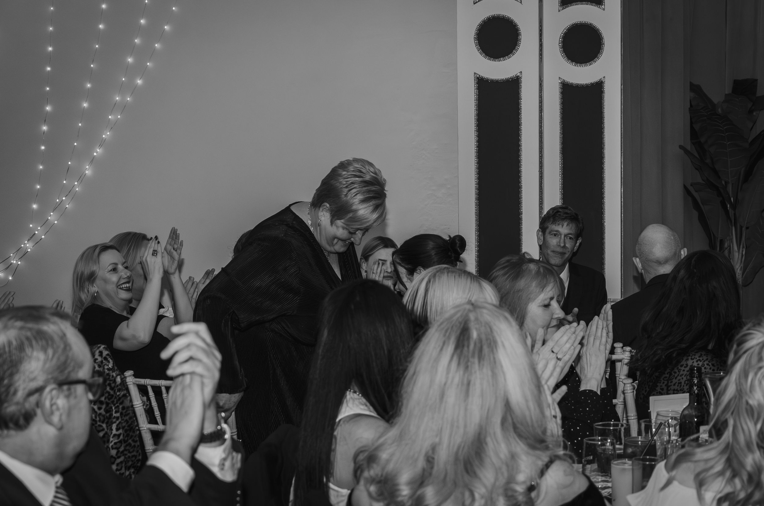 Black and white photo of guests celebrating and raising glasses during a formal dinner event.