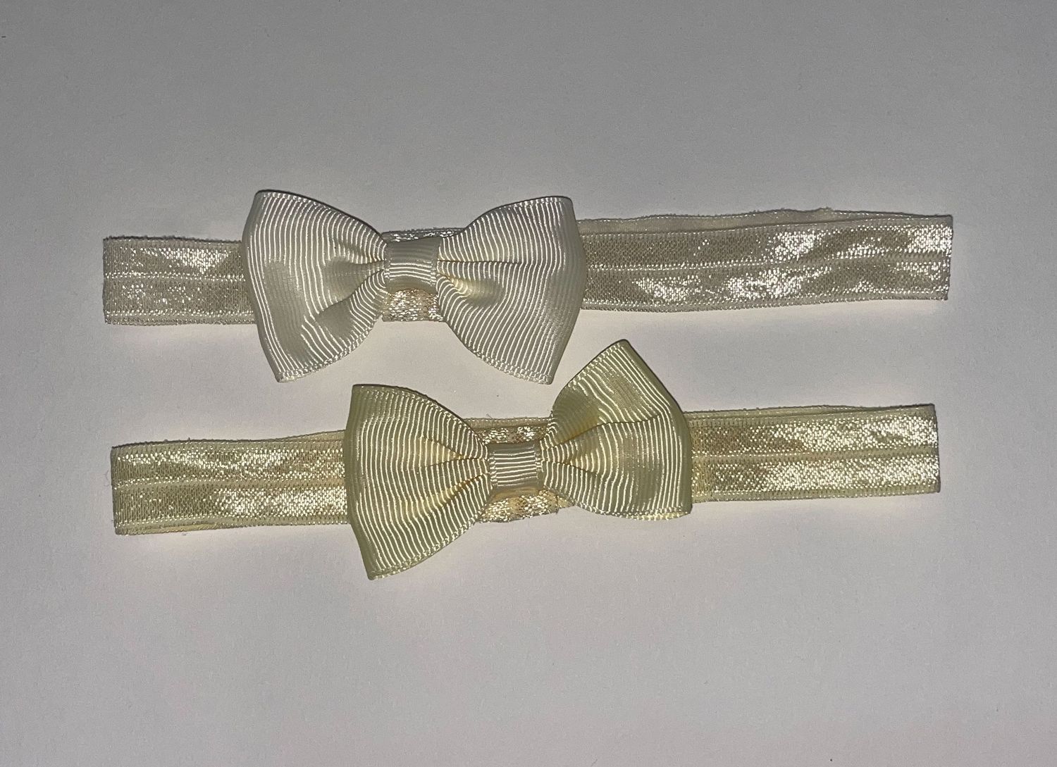 Cream colored grosgrain ribbon bow headbands arranged horizontally.