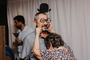 People enjoying a photo booth moment with props including a top hat and glasses.