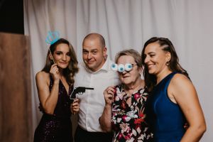 A group poses with fun photo booth props against a white backdrop at a party.