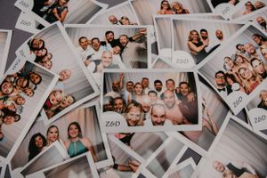 Collection of photo booth strips scattered showing various group shots and poses.