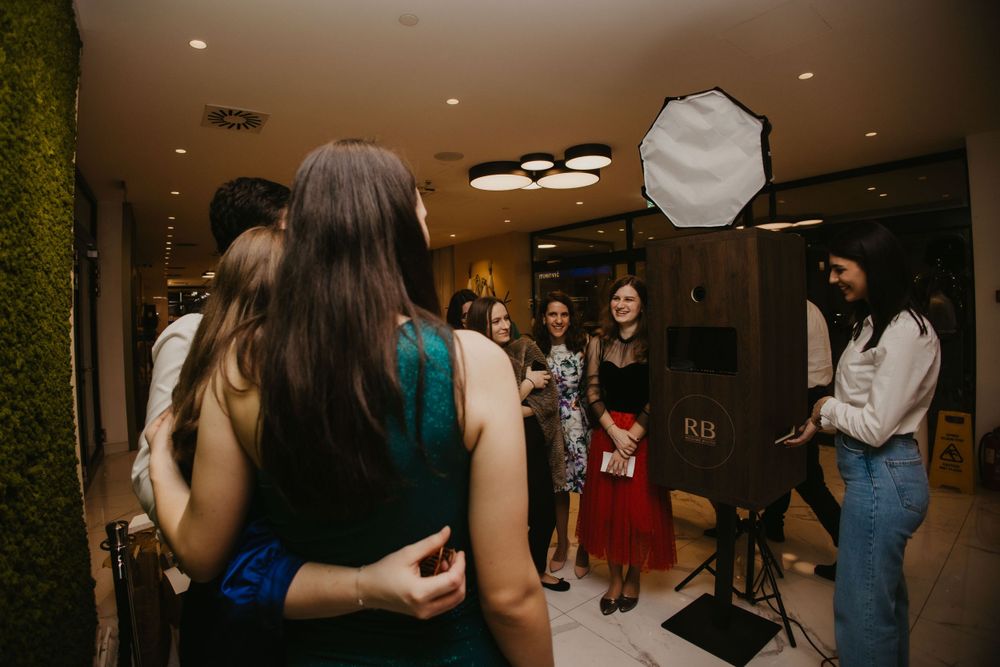 Behind-the-scenes view of a photo booth setup with lighting equipment and guests.