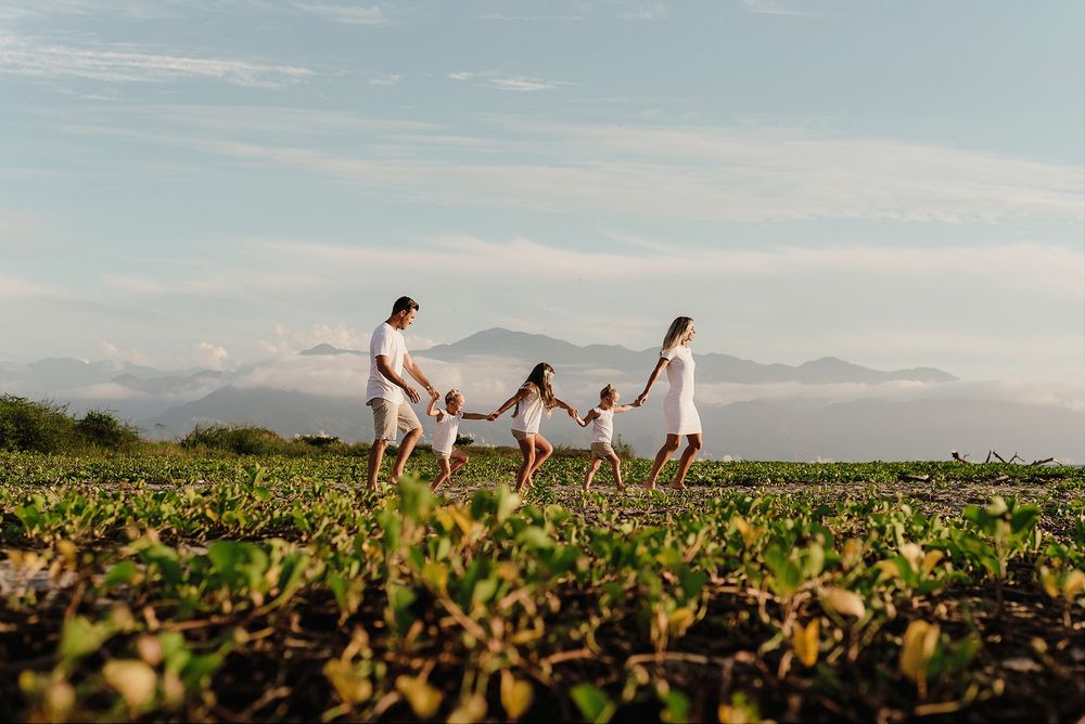 A family walking together through a green field with mountains in the background.