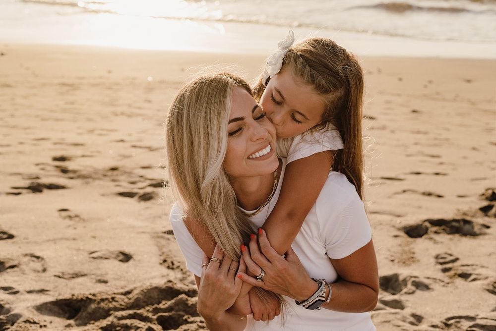 A tender moment of affection shared between two people on a sandy beach.