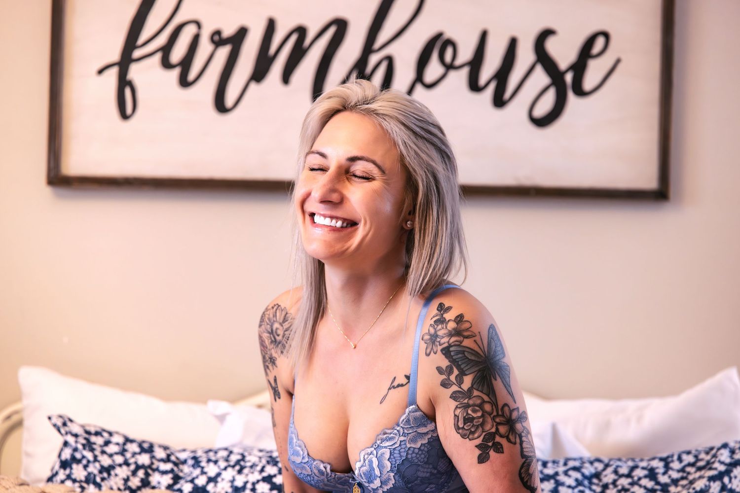 Casual portrait against farmhouse decor showing genuine laughter and artistic tattoos.
