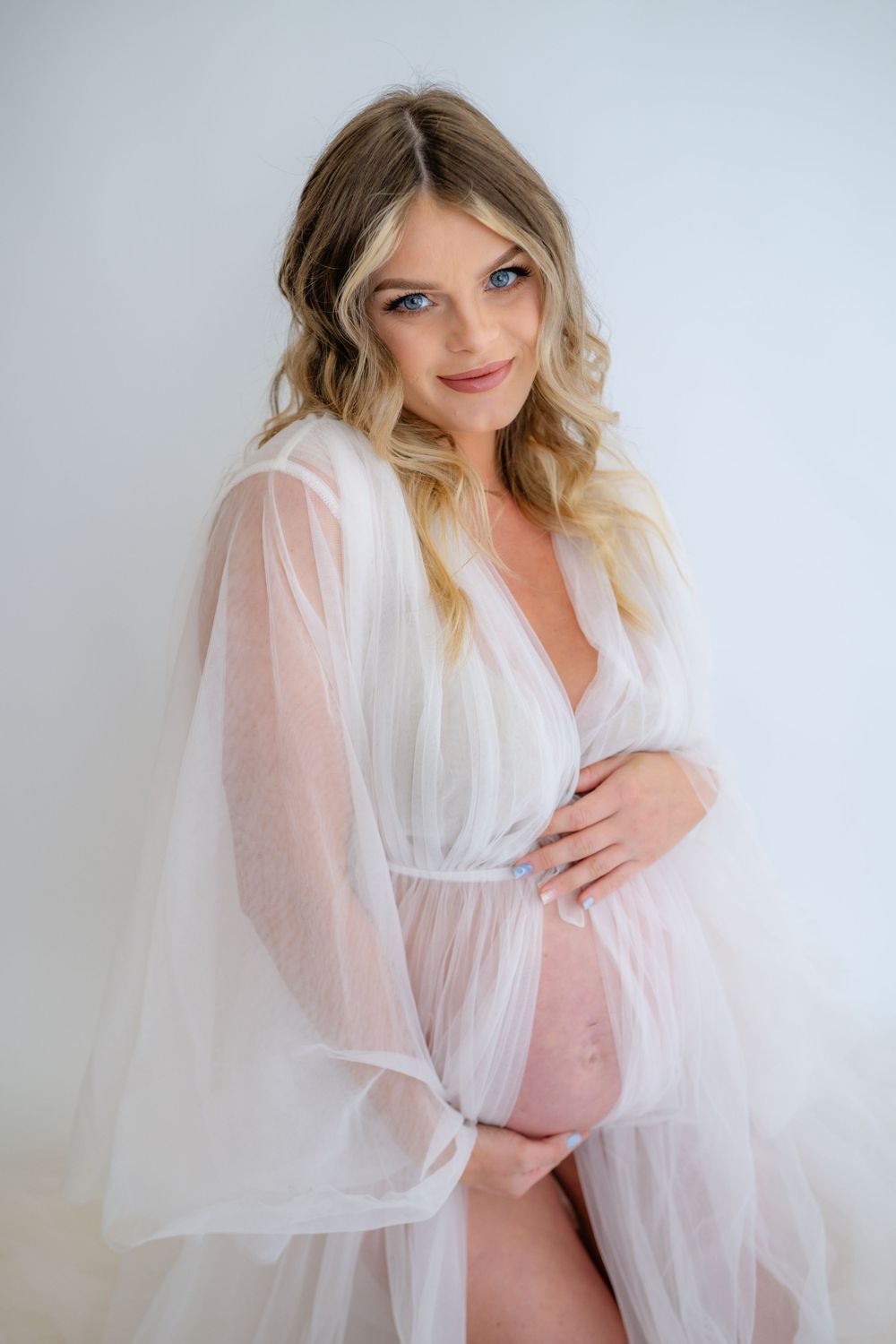 Dreamy studio maternity photo with delicate white sheer robe.